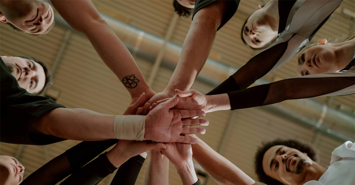 Mixed group of men and women in a circle doing a team or unity hand-stack